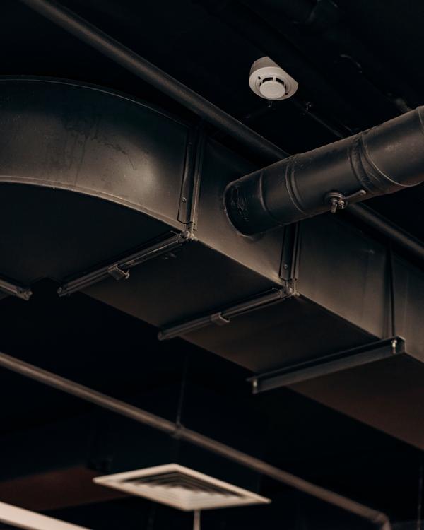 Exposed ductwork with a branch damper, and a ceiling diffuser below.