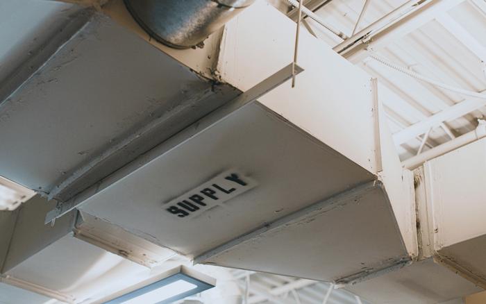 Painted supply air ductwork under an exposed ceiling, stencilled SUPPLY.