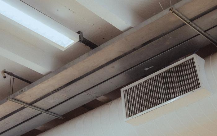 Rectangular ductwork on hangers, with a supply air grille.